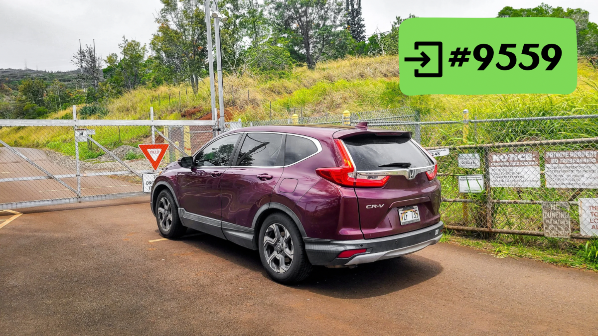 Purple SUV parked near a chain-link gate with signs and a #9559 entry code key.
